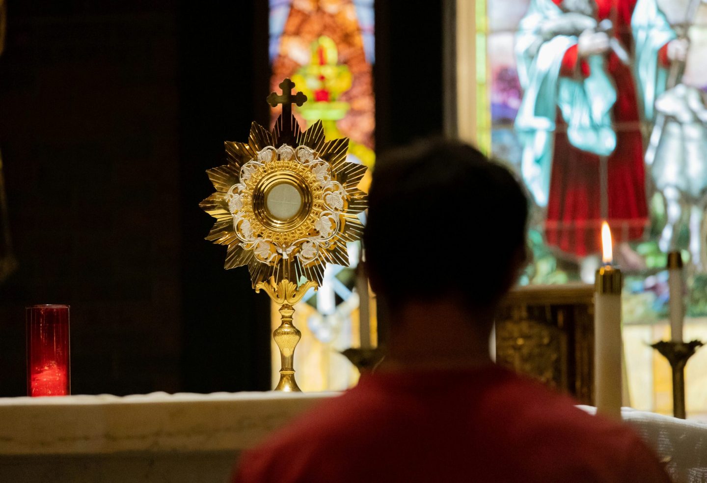 A young person kneeling in prayer before the Blessed Sacrament during adoration